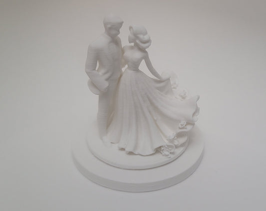 White wedding cake topper with a couple on a plain white background