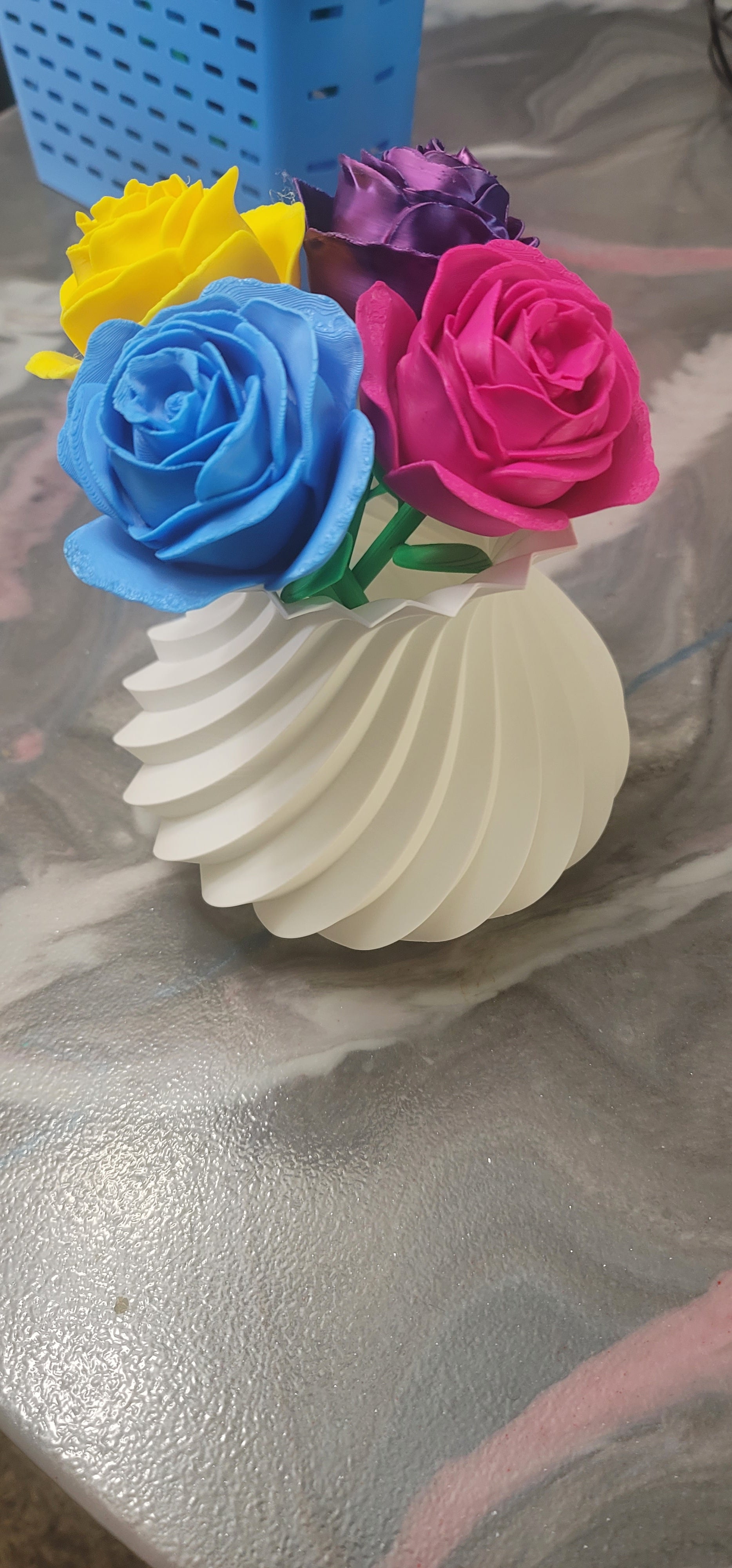 Side view of colorful 3D printed rose bouquet with yellow, blue, purple, and pink roses in a white spiral vase