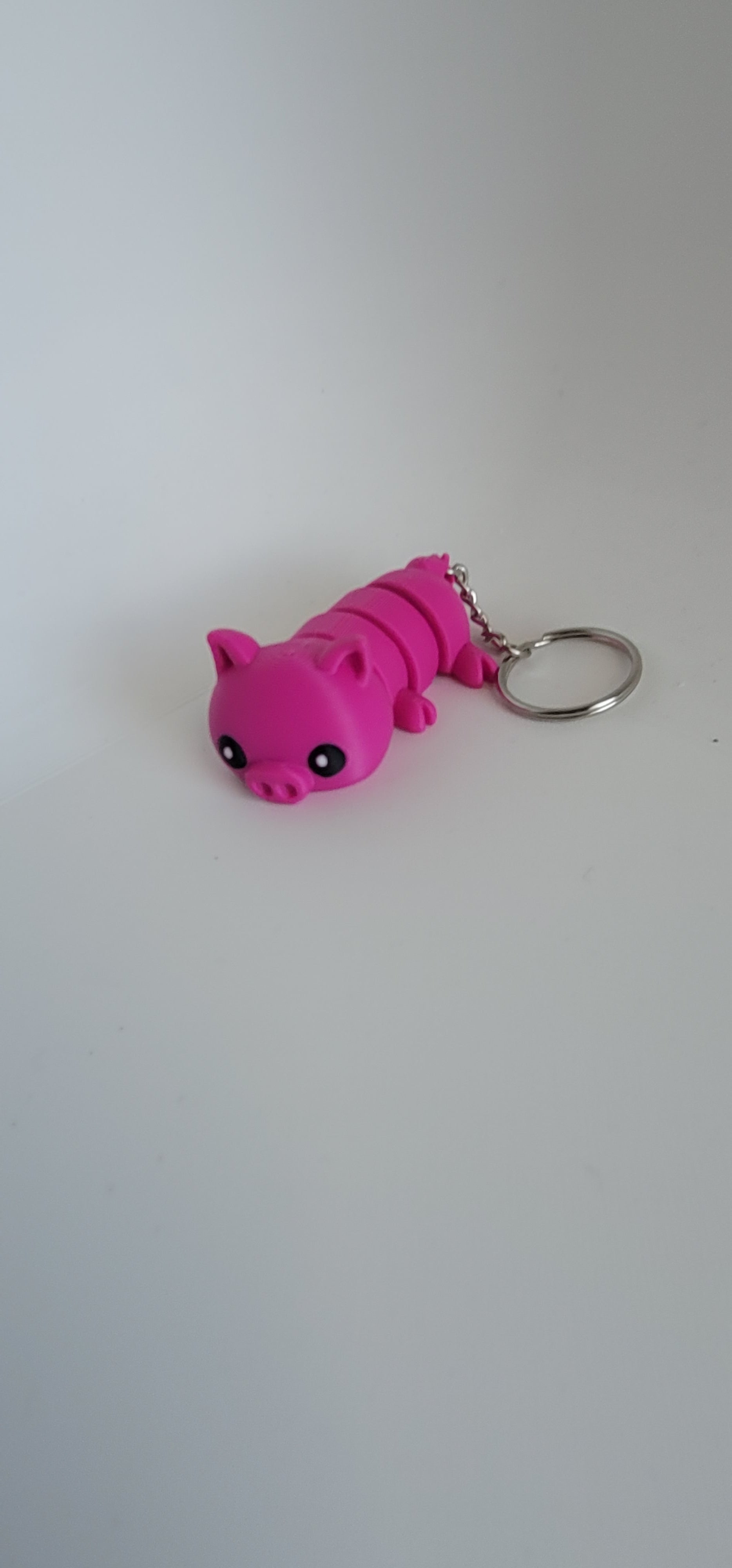 Flexi pig keychain side view showing articulated joints, 3D printed fidget toy, Woody Burns