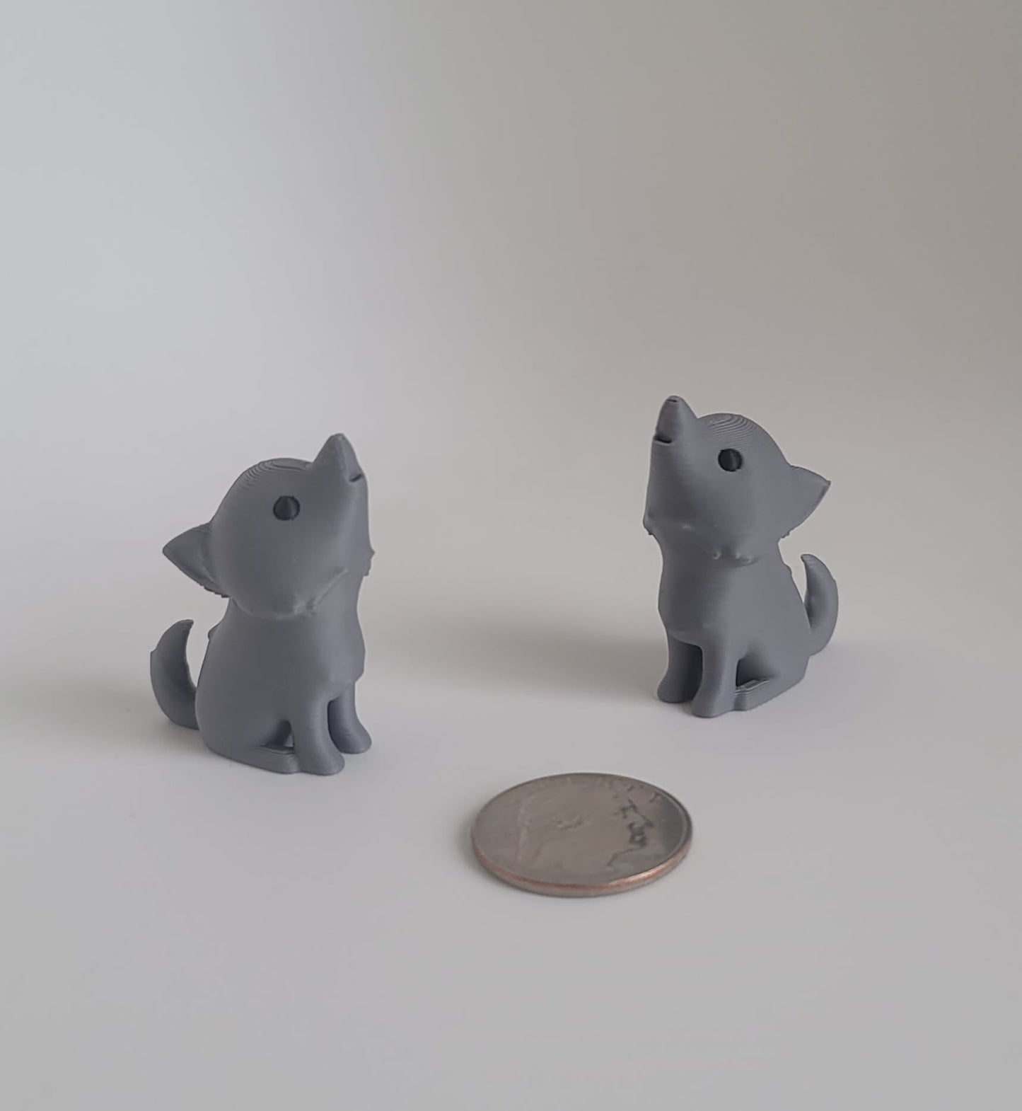 Gray 3D printed dire wolf keychain pair, rear angle view with quarter for scale, Woody Burns Home Creations Reno NV