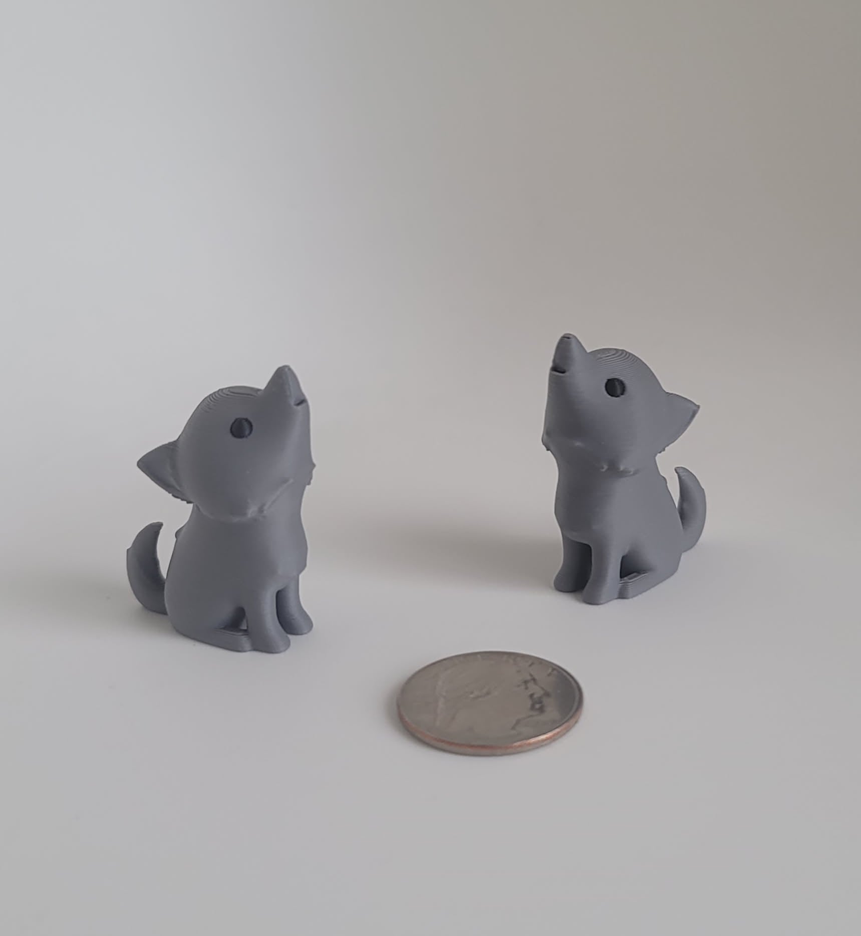 Gray 3D printed dire wolf keychain pair, rear angle view with quarter for scale, Woody Burns Home Creations Reno NV