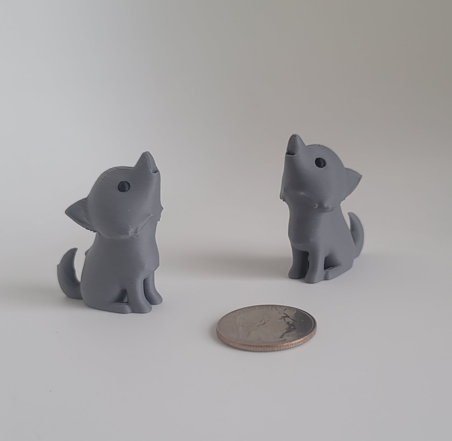 Gray 3D printed dire wolf desk toy and keychain side profile with quarter for scale, handmade in Reno NV
