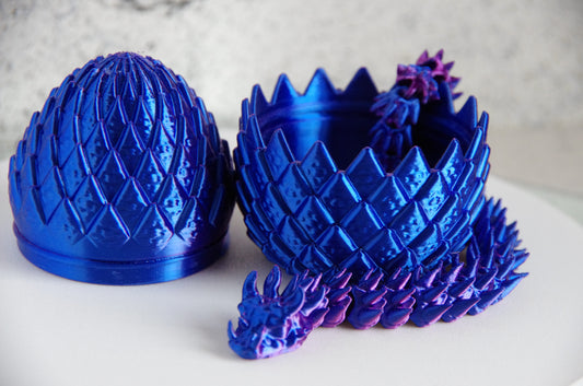 Blue dragon egg and scale model on a white surface