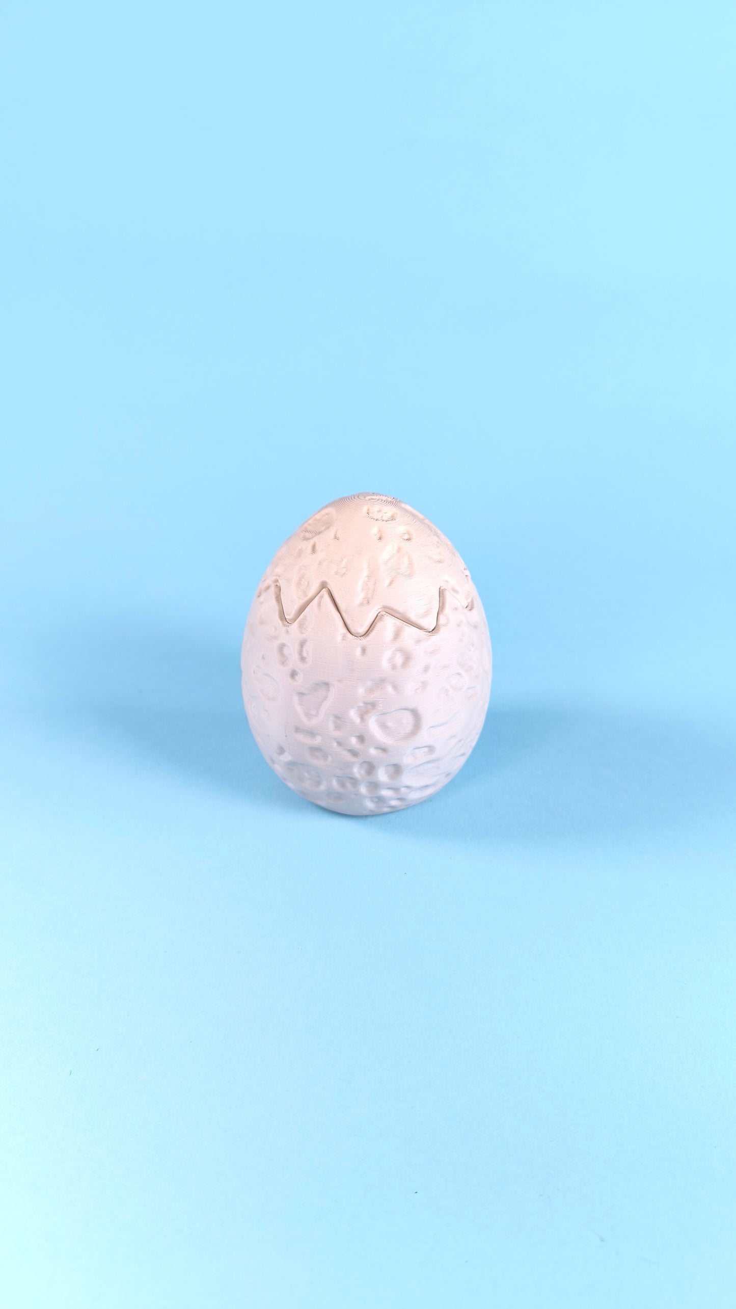 Single 3D printed dino egg with cracked zigzag detail on a light blue background