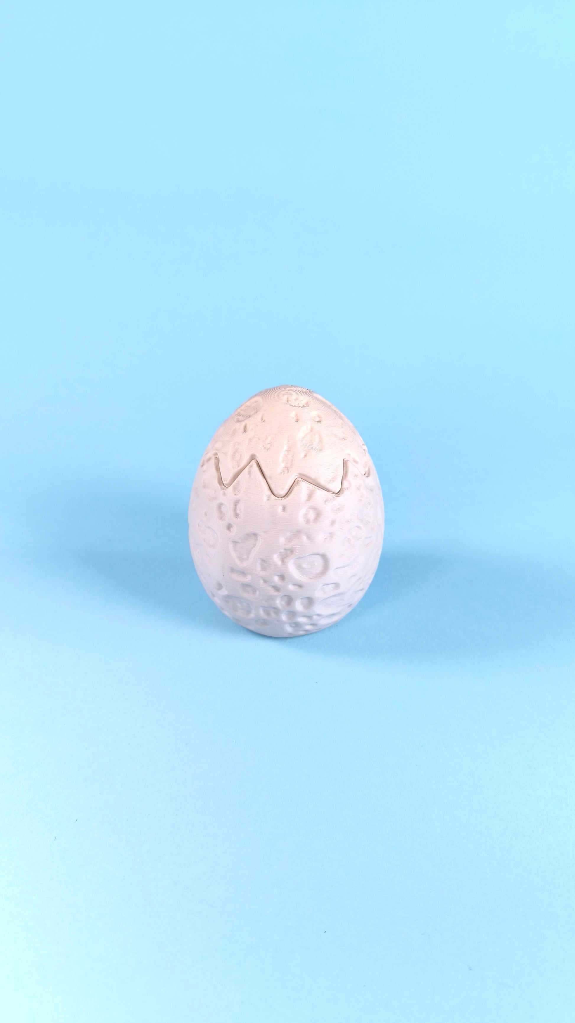 Single 3D printed dino egg with cracked zigzag detail on a light blue background