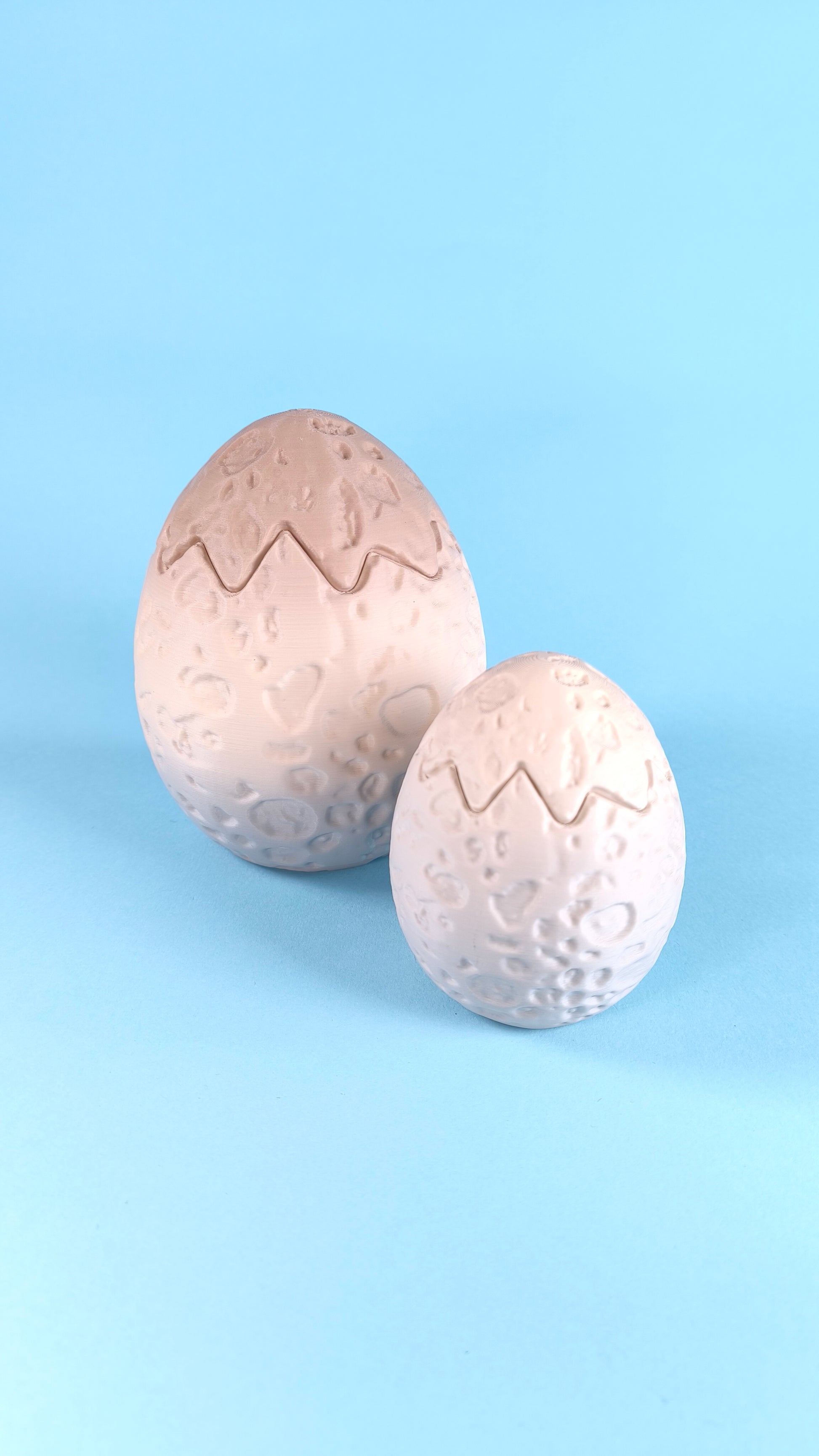 3D printed dino egg cracked open with shell cap removed, showing hollow interior where the baby dinosaur finger puppets sit